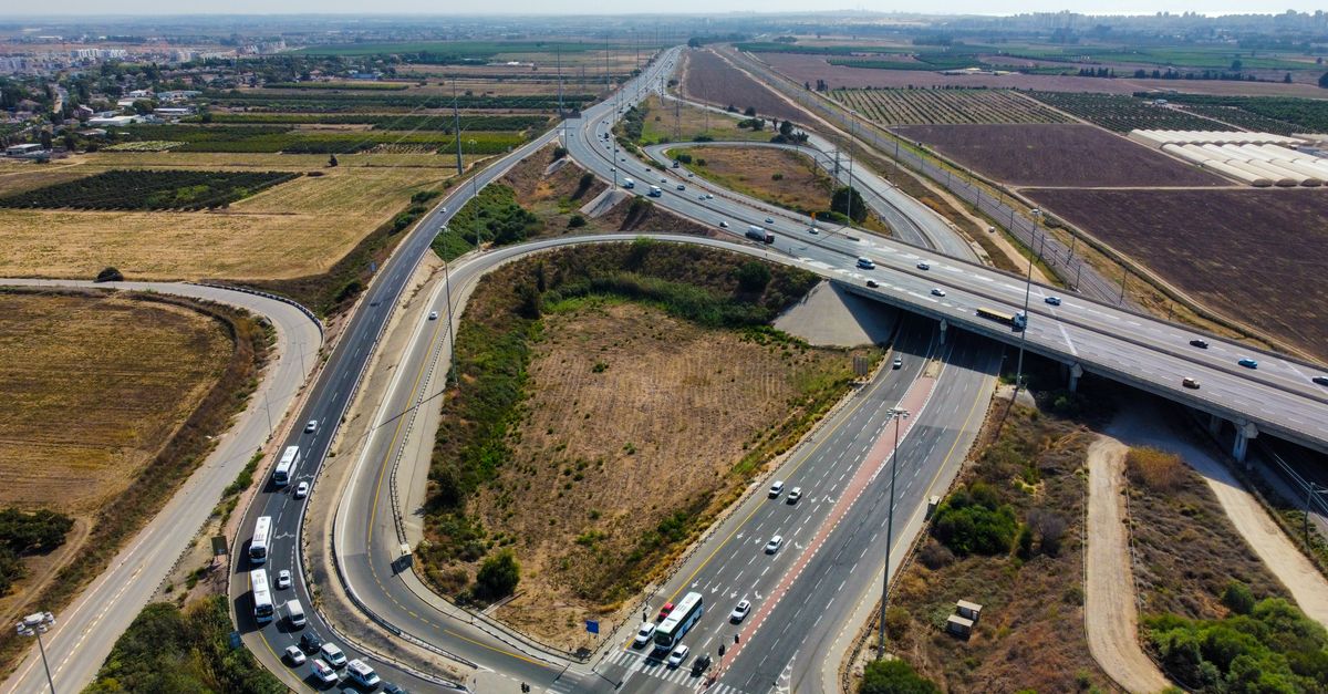 Aerial view capturing a busy highway intersection surrounded by agricultural fields and open landscape.